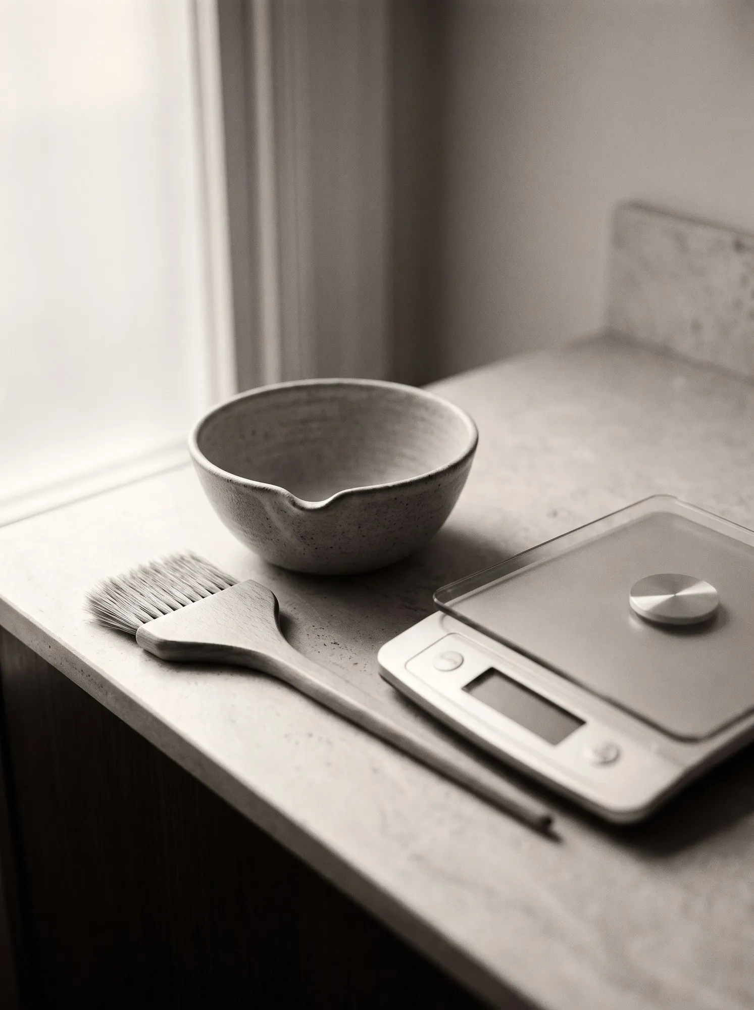A tinting bowl, colour brush and digital scales laid out on a worktop
